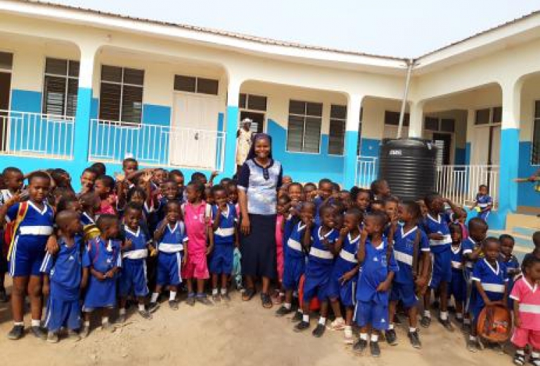 Mädchen und Jungen stehen vor einer Schule in Afrika